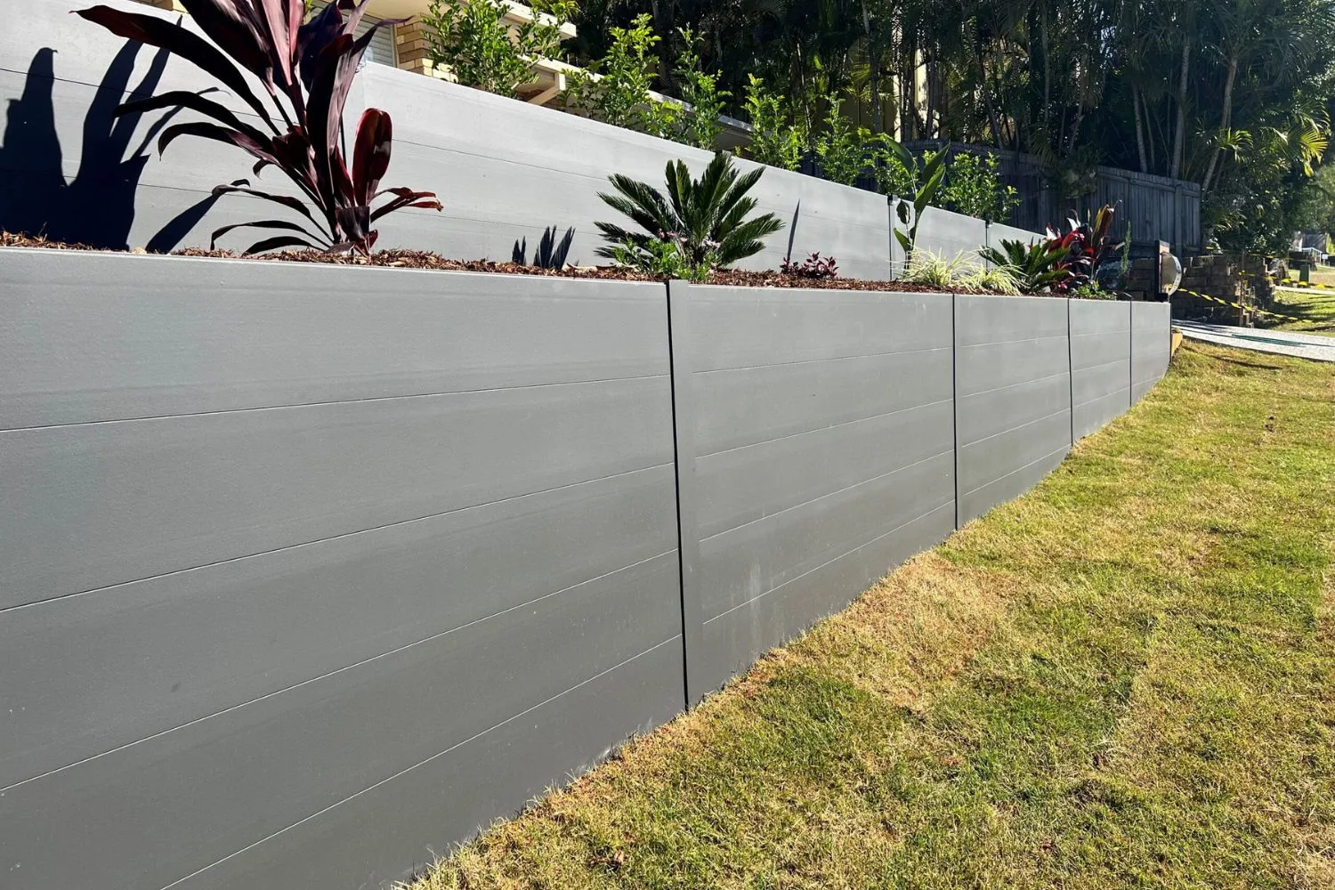 Modern concrete panel retaining wall with a raised garden bed on top