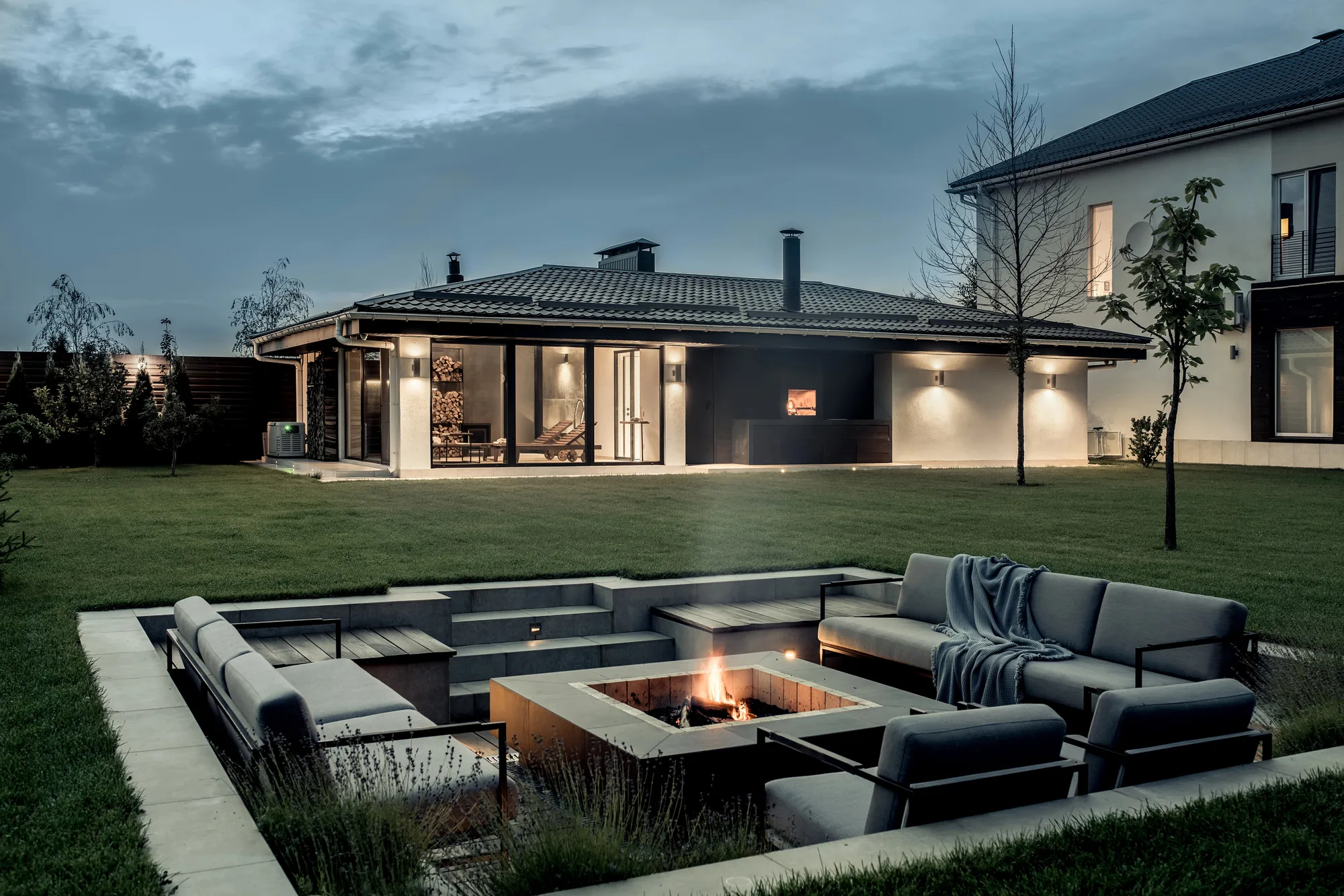 Sunken outdoor lounge with in-ground fire pit at dusk