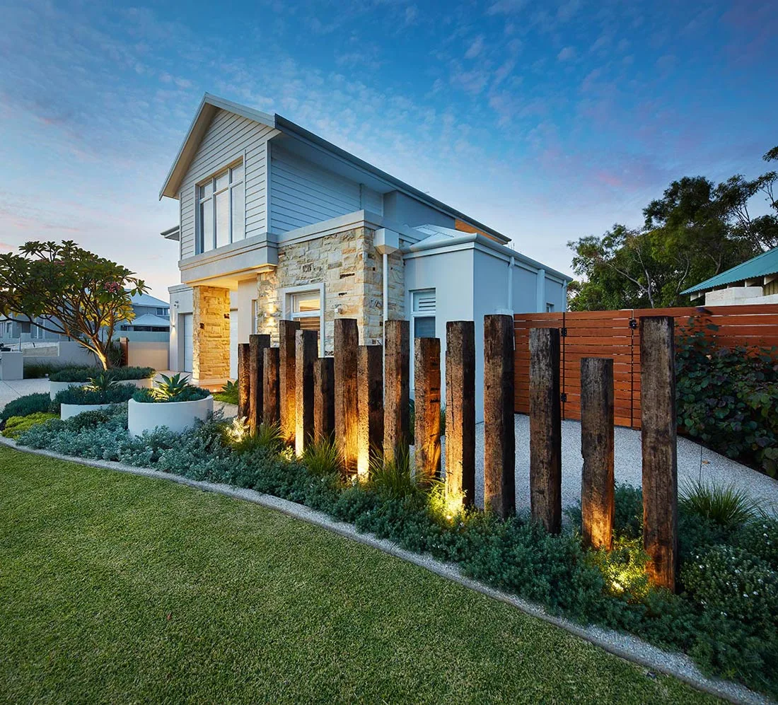 Timber sleeper retaining wall feature with garden lighting at dusk