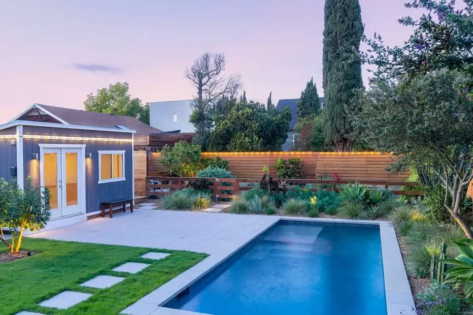 Backyard swimming pool with landscaped garden surrounds and deck