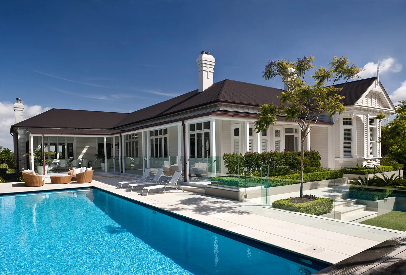 Backyard swimming pool with landscaped surrounds beside a federation-style home
