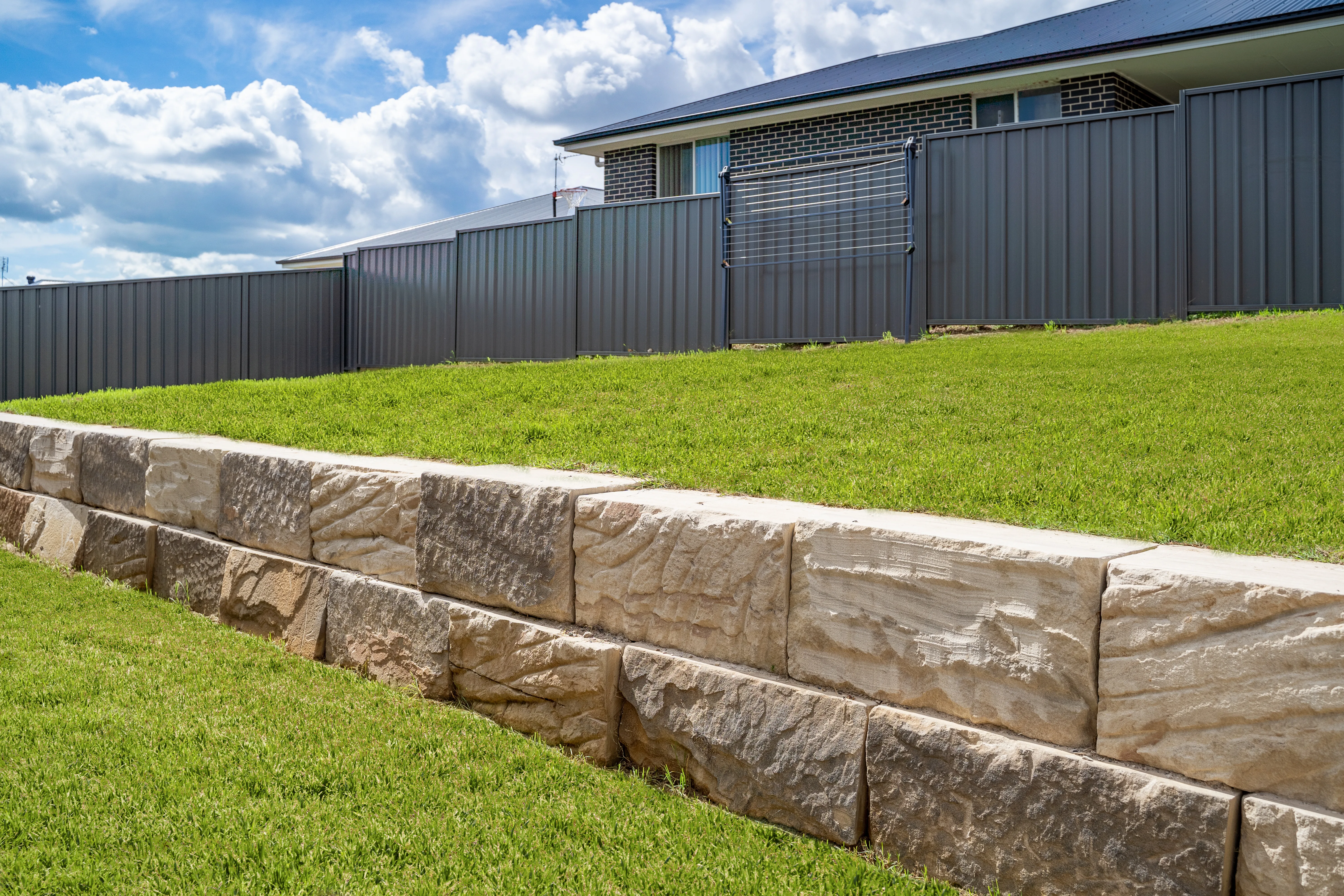 Sandstone block retaining wall holding back a sloping backyard
